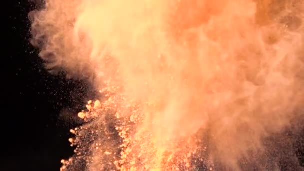 Super slow motion explosie van kleurrijk oranje poeder op donkere geïsoleerde achtergrond. Stukjes poeder vliegen omhoog en mengen met de rook. — Stockvideo