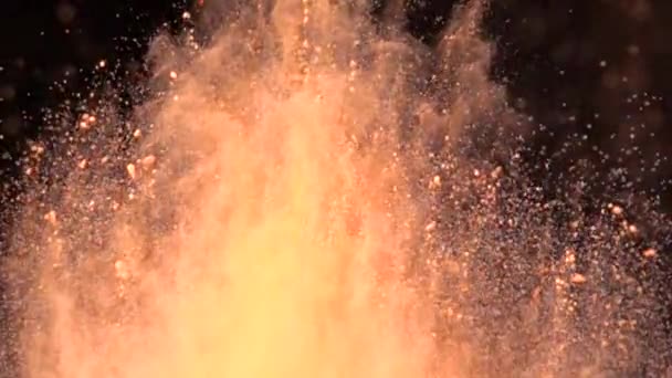 Super Zeitlupe Explosion von buntem, orangefarbenem Pulver auf dunklem, isoliertem Hintergrund. Puderklumpen fliegen nach oben und vermischen sich mit dem Rauch. — Stockvideo