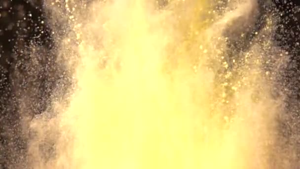 Super slow motion explosie van kleurrijk geel poeder op donkere geïsoleerde achtergrond. Stukjes poeder vliegen omhoog en mengen met de rook. — Stockvideo