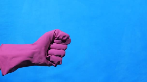 Рука с фиолетовой резиновой перчаткой указывает на синий фон — стоковое видео