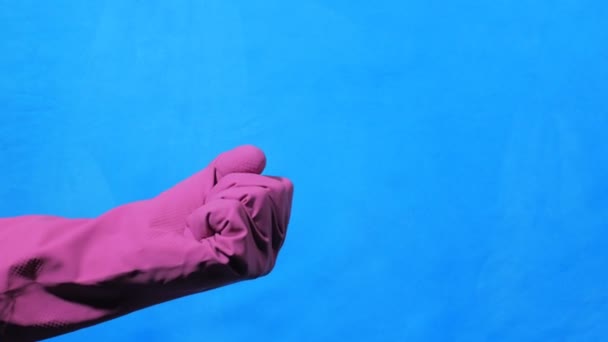 Более чистая рука в фиолетовой резиновой перчатке на синем фоне. Fuck . — стоковое видео
