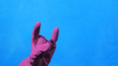 Mor lastik eldiven mavi zemin üzerine temiz elinde. Rock ve metal jest.