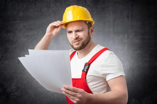 Confused construction worker holding papers