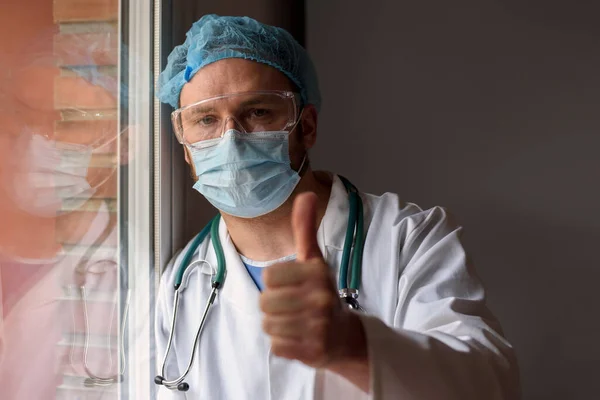 Läkare i ansiktet mask visar tummen upp tecken — Stockfoto