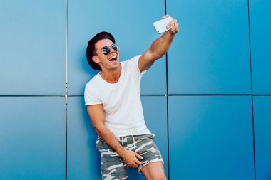 Neşeli adam akıllı telefonda bir selfie alır, açık havada.