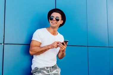 Akıllı telefon ile neşeli adam, açık havada ayakta.