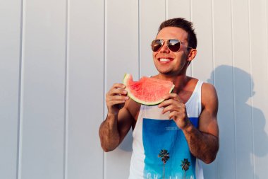 Bir karpuz yiyen gülümseyen adam, açık havada