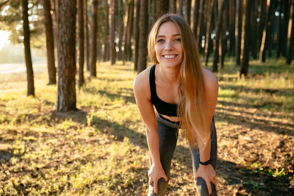 Mujer alegre haciendo ejercicios de estiramiento en el bosque — Foto de Stock