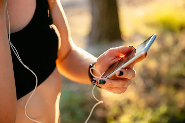 Vista de cerca de la mujer fitness utilizando un teléfono inteligente al aire libre — Foto de Stock