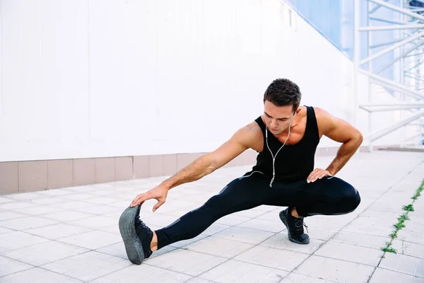 Hombre deportivo estirando su cuerpo durante el entrenamiento al aire libre — Foto de Stock