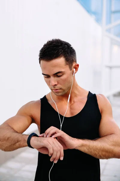 Deportista comprobando un tiempo en los relojes inteligentes después del entrenamiento al aire libre — Foto de Stock