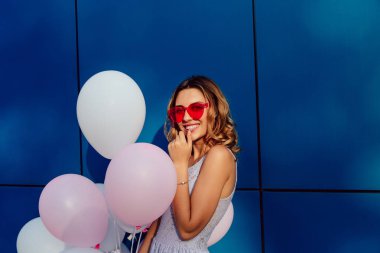 Kırmızı güneş gözlüğü charming kadın dışında, hava balonları tutar