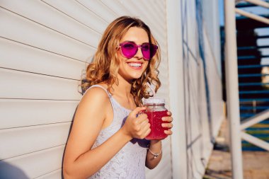 Güneş gözlüğü içinde Charming kadın meyve içecek içme, dışında.
