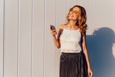 Kulaklıkta akıllı telefondan müzik dinleyen sevimli kız