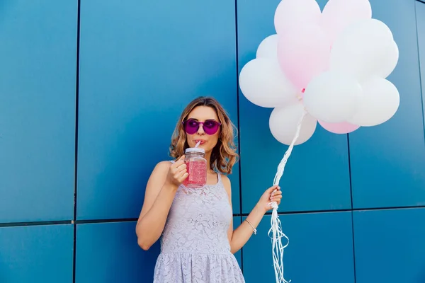 Snygg tjej dricker kall smoothie, stående utomhus med Luftballonger — Stockfoto