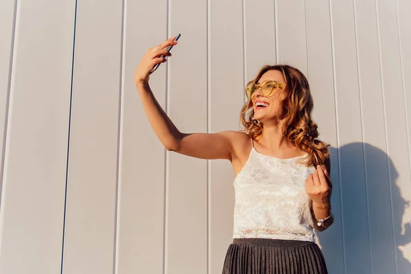 Szczęśliwa kobieta bierze selfie na smartfonie, stojąc na zewnątrz — Zdjęcie stockowe