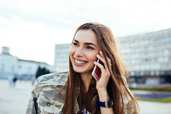 Fröhliches Mädchen, das lustige Gespräche per Handy führt, im Freien spazieren geht — Stockfoto