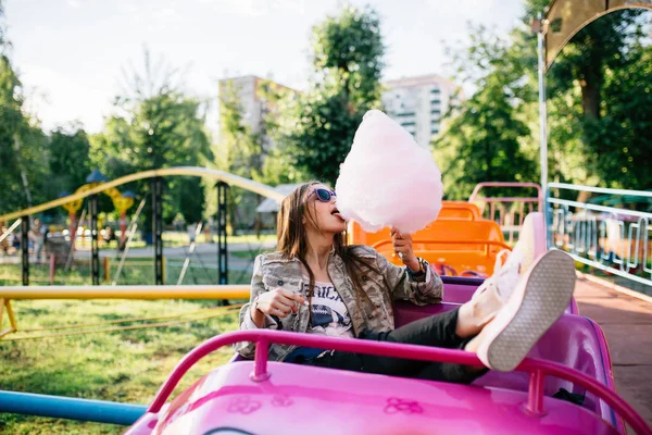 Ελκυστικό κορίτσι τρώει ένα μαλλί της γριάς, ενώ κάθονται στο τρενάκι του λούνα παρκ — Φωτογραφία Αρχείου