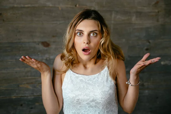 Attractive woman looks shocked spreading her hands out — Stock Photo, Image