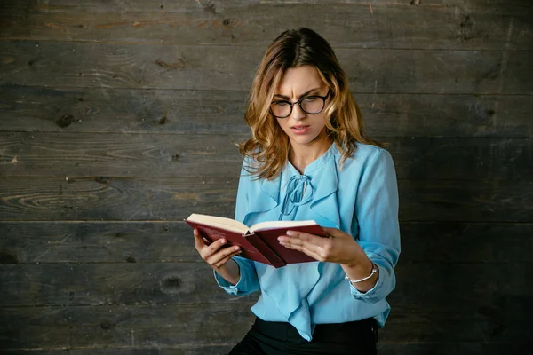 Hübsche Frau mit verwirrtem Gesicht beim Lesen eines Buches — Stockfoto
