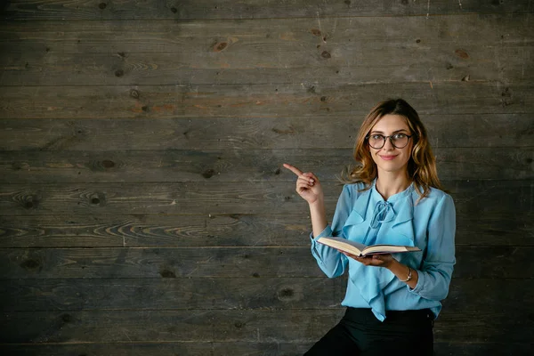 Attraktive Frau hält aufgeschlagenes Buch und zeigt Kopierraum auf grau — Stockfoto