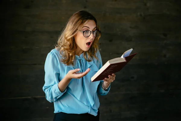 Schöne Frau schockiert über etwas beim Lesen eines Buches — Stockfoto