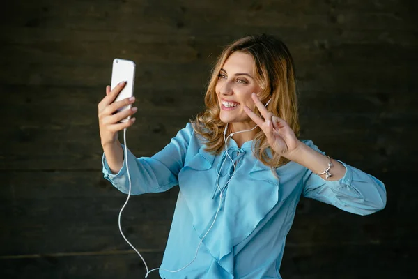 Uśmiechnięta dziewczyna biorąc selfie na smartfonie — Zdjęcie stockowe