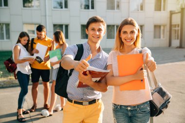 Not defteri ve sırt çantaları ile mutlu iki genç öğrenci gülümseyen