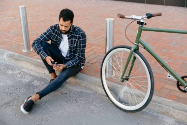 Akıllı telefonlarını kullanarak kulaklıklı şık adamın üstten görünümü, açık havada.