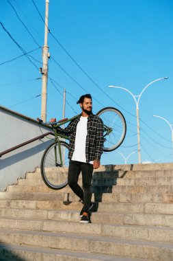 Merdivenlerden inerken omzuna bisiklet tutan neşeli adam