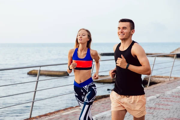 Alegre pareja trotando juntos cerca del mar — Foto de Stock