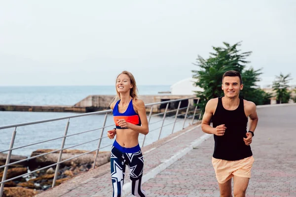 Pareja feliz corriendo en el muelle cerca del mar — Foto de Stock