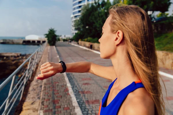 Mujer revisando un tiempo en sus relojes inteligentes después de correr al aire libre — Foto de Stock