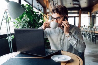 Gözlüklü işadamı p konuşurken kahve içiyor