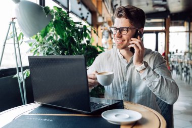 Neşeli işadamı co içerken telefon görüşmesi yapıyor