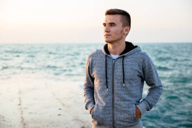 İskelede, denizin yanında duran düşünceli sporcu