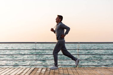 Spor takım elbiseli adam, rıhtımda koşuyor, denize yakın