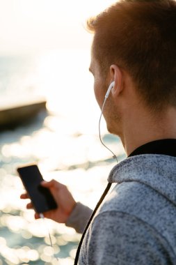 Okyanus yakınında duran akıllı telefon ile adam geri görünümü
