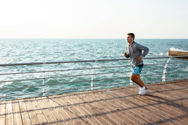 Spor giyimli adam, rıhtımda koşuyor, denize yakın