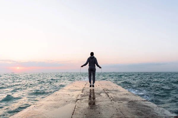 Vista desde atrás del deportista saltando con la cuerda, en el muelle — Foto de Stock