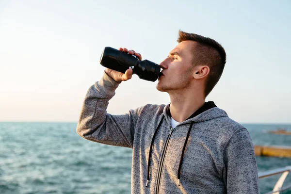 Joven deportista bebiendo agua después del entrenamiento al aire libre — Foto de Stock