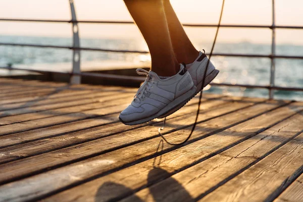 Foto de primer plano de las piernas masculinas en vuelo con saltar la cuerda, cerca del mar — Foto de Stock