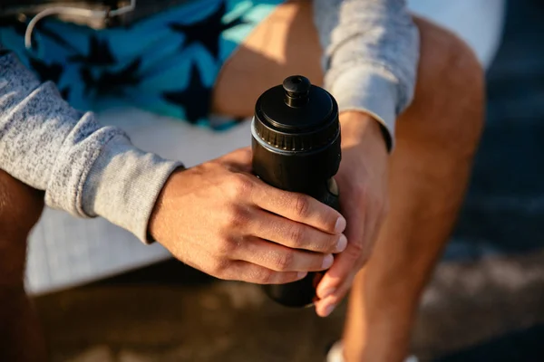 Foto de cerca de manos masculinas sosteniendo una botella con agua — Foto de Stock