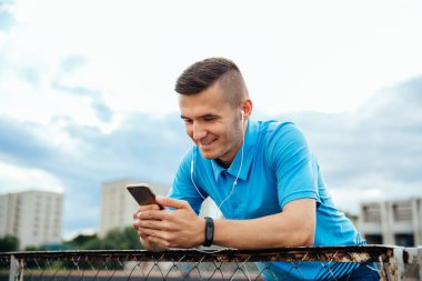 Gülümseyen adam kulaklık ile cep telefonu içine bakıyor