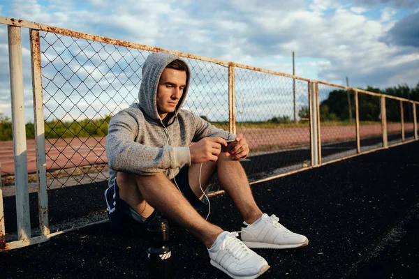 Mobil uygulama kullanarak sportif adam oturma — Stok fotoğraf