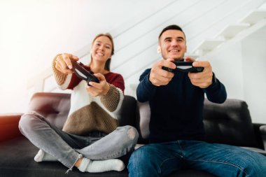 Gülümseyen kız ve adam joystick kullanarak video oyunları oynuyor