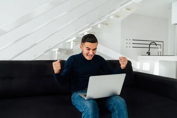 Podekscytowany człowiek świętować swój sukces po wygranej, za pomocą laptopa w domu. — Zdjęcie stockowe