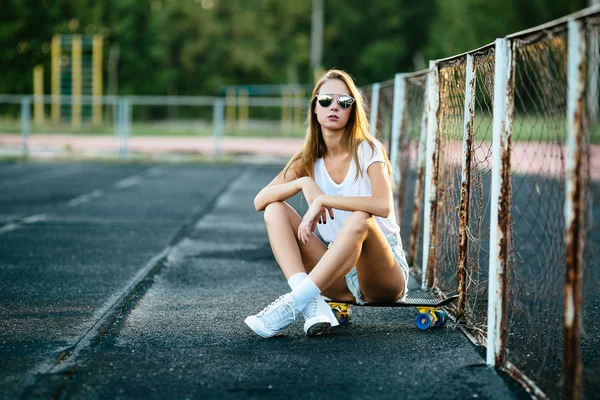 Krásná Dívka Sluneční Brýle Sedí Blízko Plotu Její Skateboard — Stock fotografie