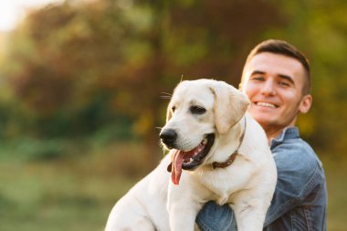 Sunset Park elinde onun köpek Labrador ile gülümseyen adam