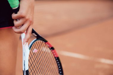 Tenis raketi kil sahada tutan kadın. Yakın çekim görünümü raket ve el.